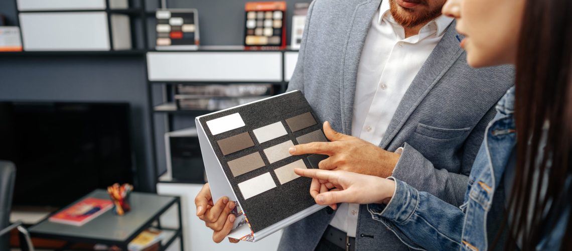 Salesman shows color swatches to lady customer for new kitchen furniture close up